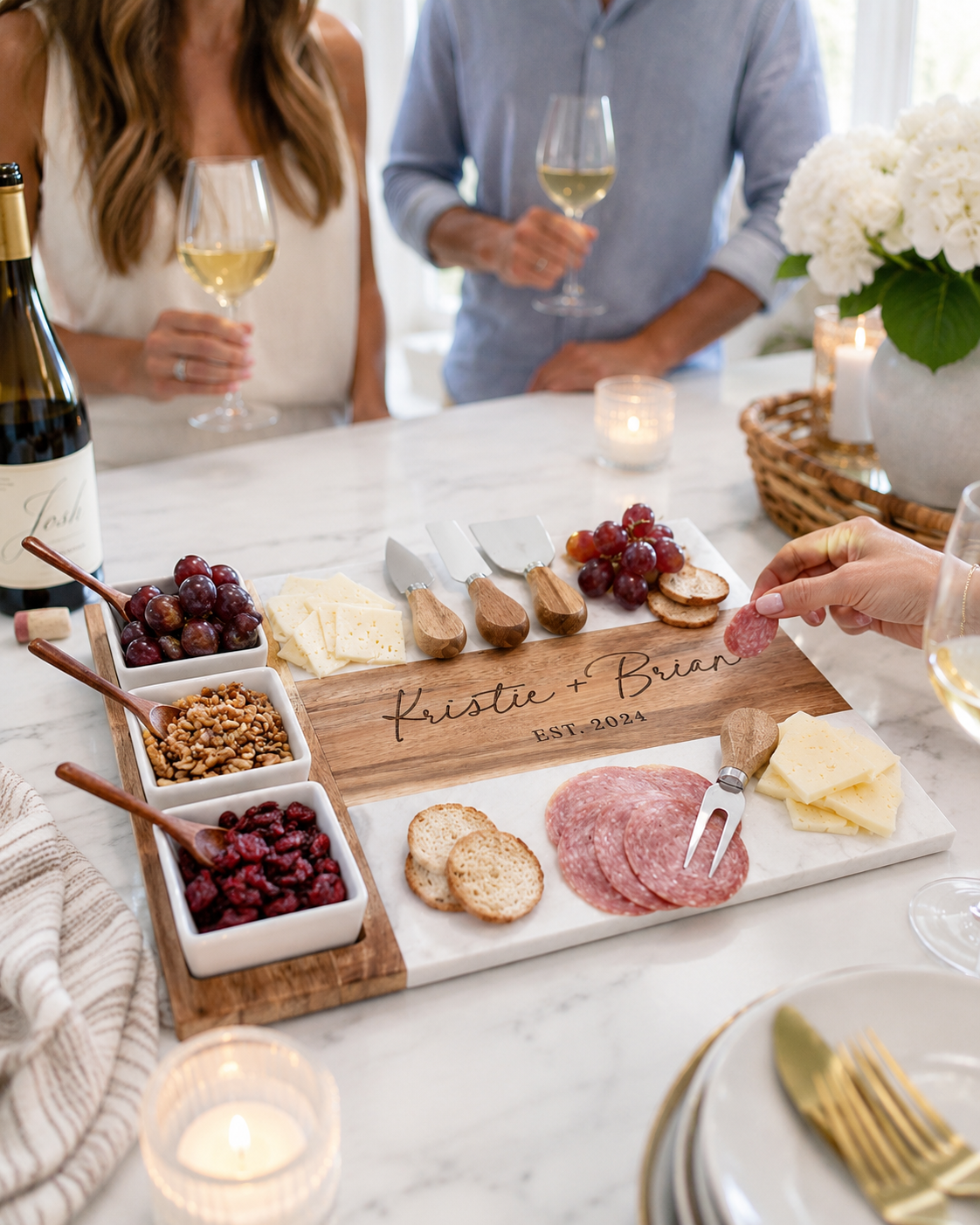 Personalized cheeseboard with food and wine on a table with people in the background