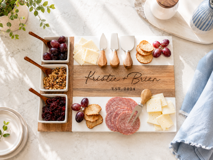 Wooden charcuterie board with meats, cheeses, and fruits on a marble surface.

